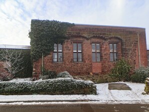 A brick building with three arched windows and a snow-covered ground. - Monastery Hall (Chester)