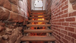 A stone-walled staircase leading to a wooden platform with a fire. - Monastery Hall (Chester)