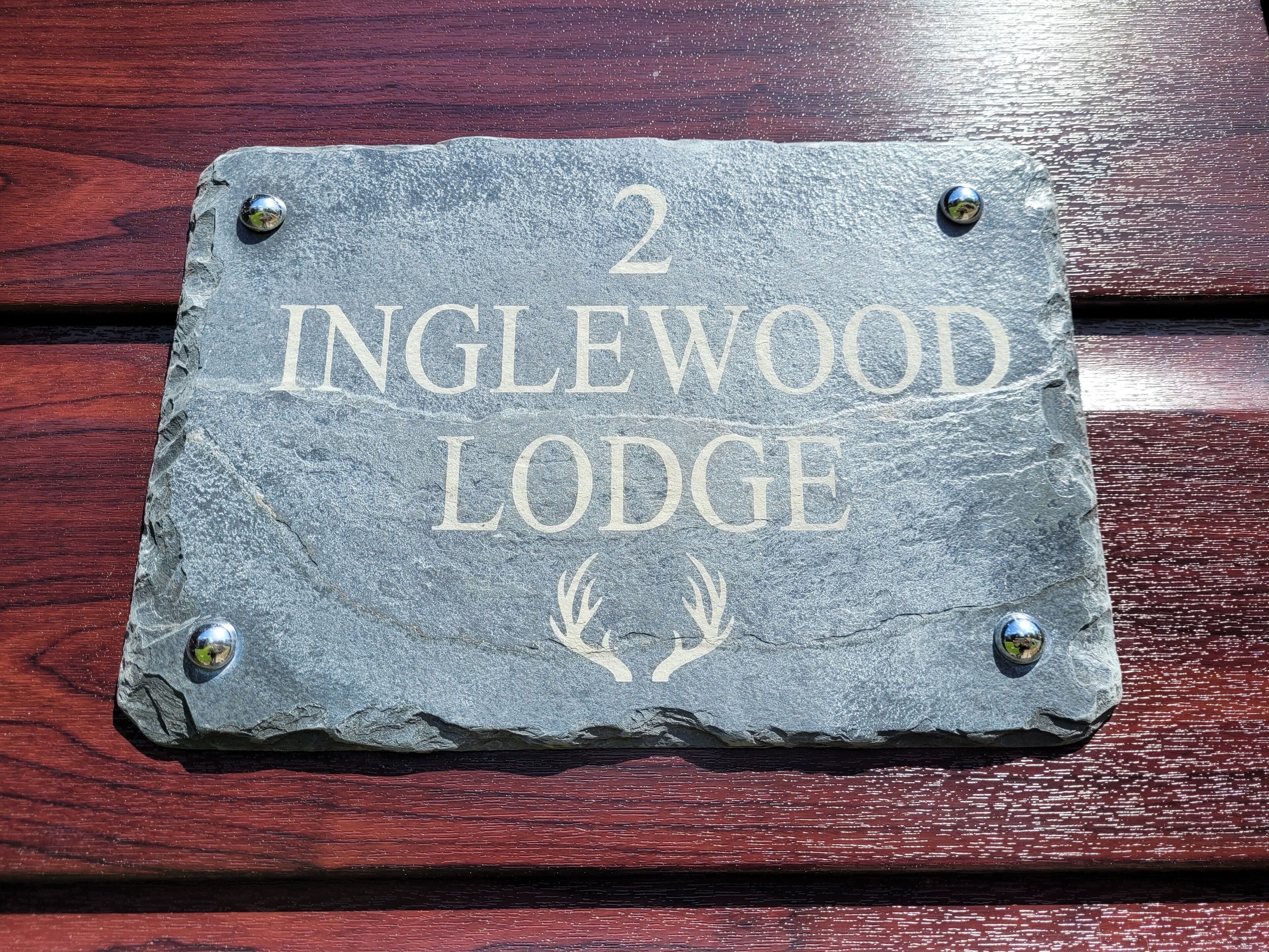 Un segnale di pietra con la scritta '2 Inglewood Lodge' e due corna di cervo, che indica un albergo chiamato Inglewood Lodge.