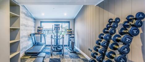 A home gym with a treadmill, elliptical, and free weights.