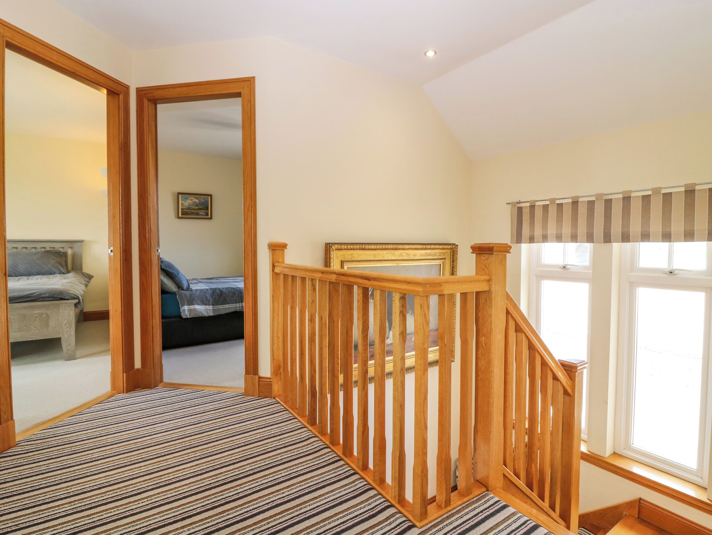 A bedroom with a bed, a wooden staircase, and a window with curtains.