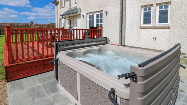 A hot tub in front of a house with a red deck and a white exterior. - Drummygar Mains (Arbroath)