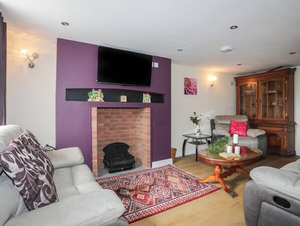 Een woonkamer met een open haard, een televisie erboven en een groot houten kast.