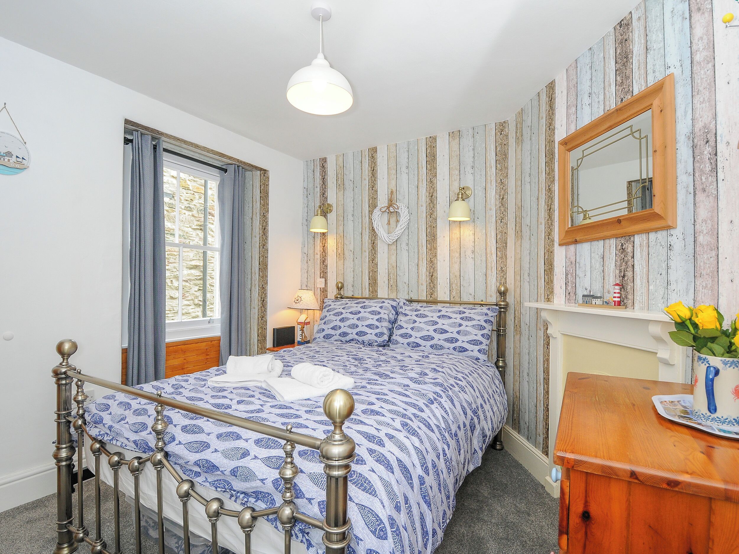 Ein Schlafzimmer mit einem Bett, einem Holzschrank, einem Spiegel und einem Fenster mit Vorhängen.
