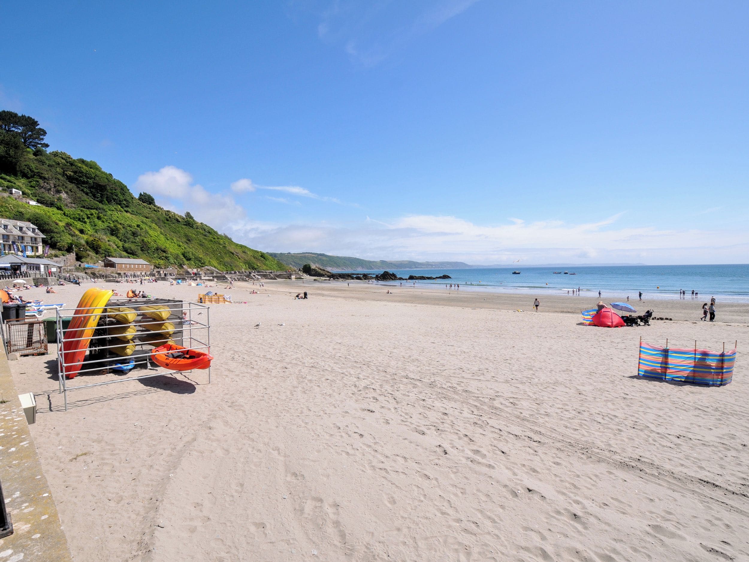 A beach with kayaks, tents, and a clear sky.