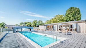 A swimming pool with a wooden deck, lounge chairs, and a covered seating area. - Lodge 62 at Riviera Bay Coastal Retreat (Brixham)