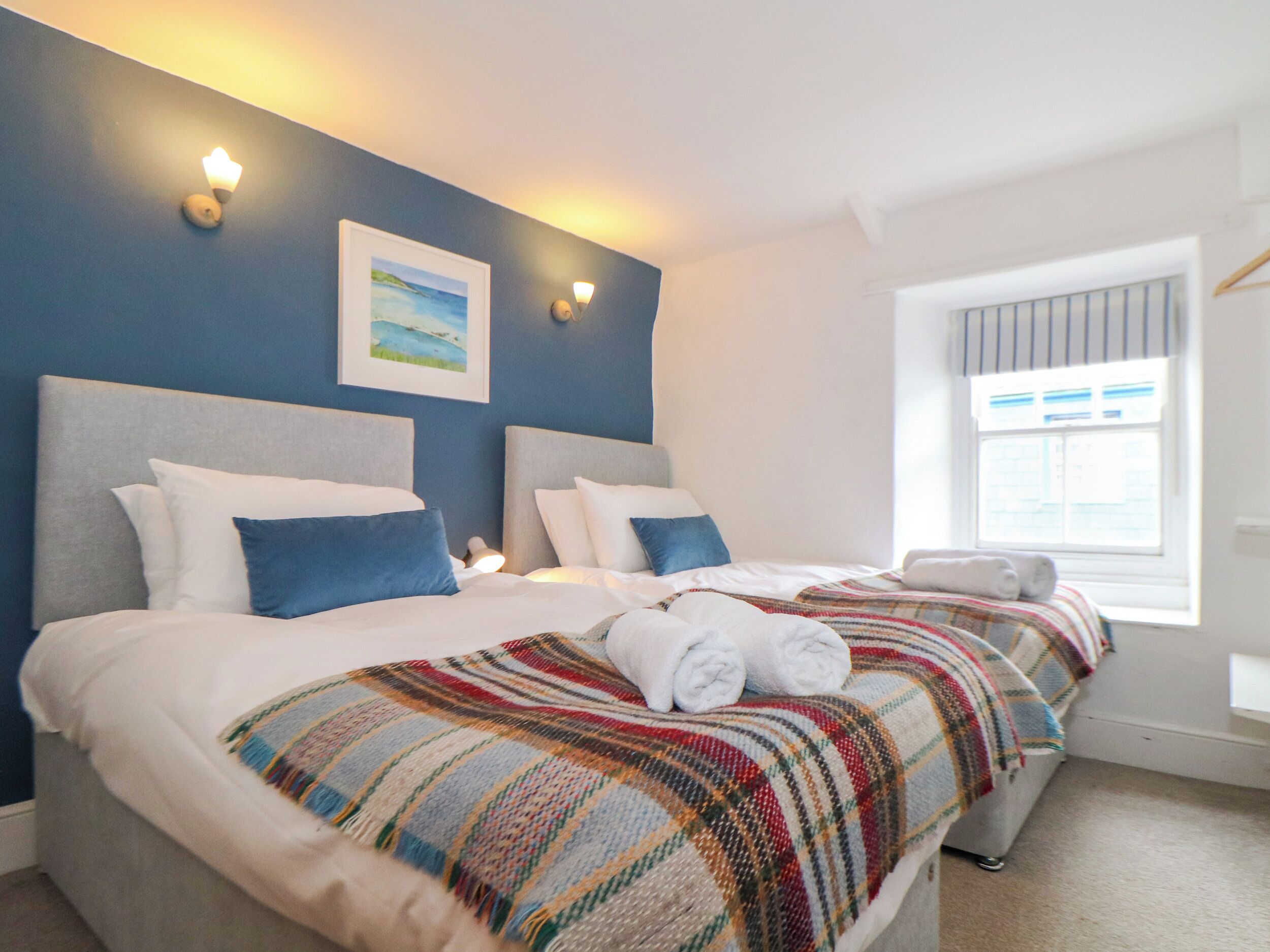 A hotel room with two beds, a large window, and a painting on the wall.