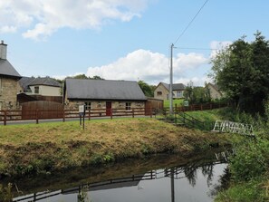 A stone building with a red door and a wooden fence in front. - Canal Cottage (Drumshanbo)