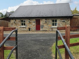 Un edificio de piedra con puerta roja, ventanas y entrada empedrada.