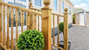 A wooden staircase with a balustrade leading to a house with a white door and windows. - Lowen Lodge (Padstow)