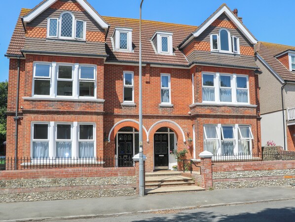 A two-story brick house with a symmetrical facade, multiple windows, and a central entrance with a black door. - The Secret Cottage 5A (Seaford)
