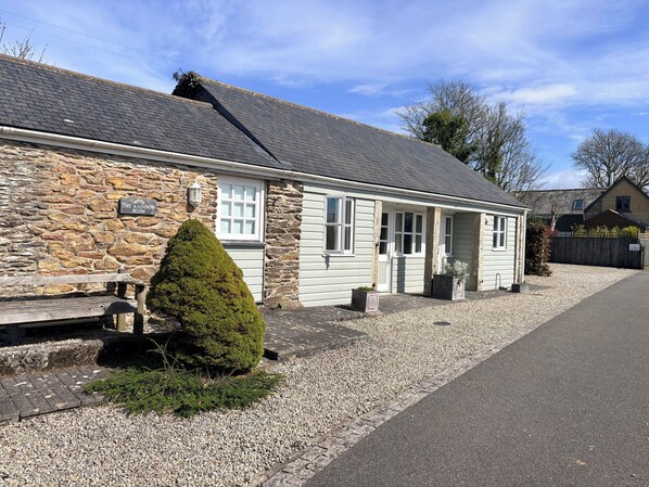 A stone building with a white facade, a small porch, and a gravel driveway.