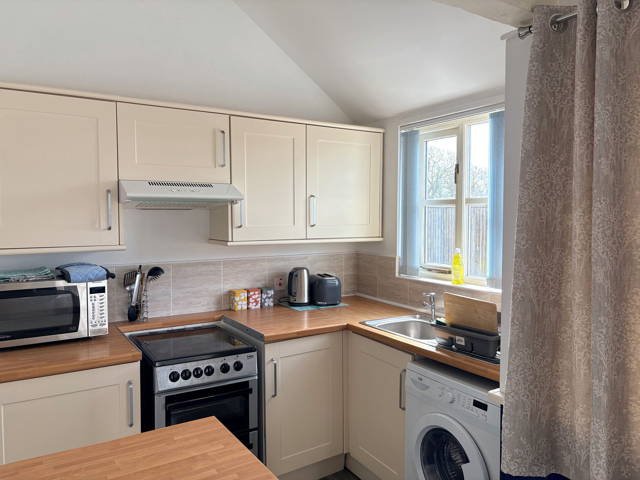 A compact kitchen with a microwave, stove, oven, and washing machine.