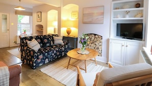 A cozy living room with a sofa, a TV, and a fireplace. - Compass Cottage (Aldeburgh)
