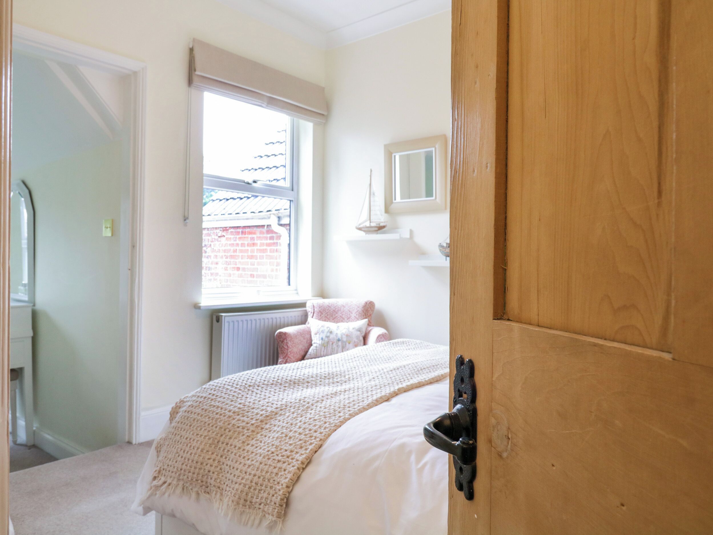 A bedroom with a bed, a window, a radiator, and a wooden door.