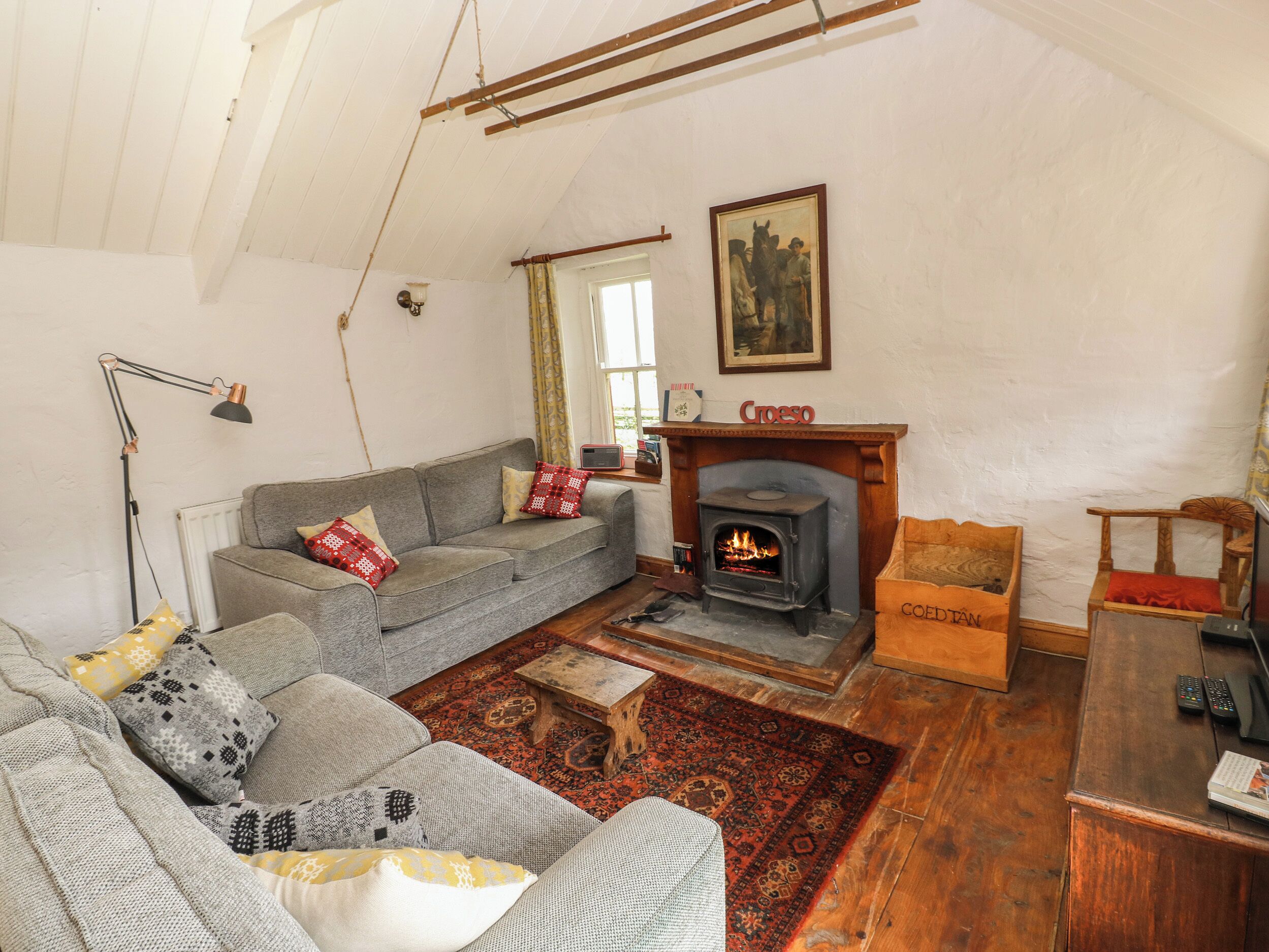 Un salon chaleureux avec une cheminée, un canapé, une chaise en bois et une petite table.