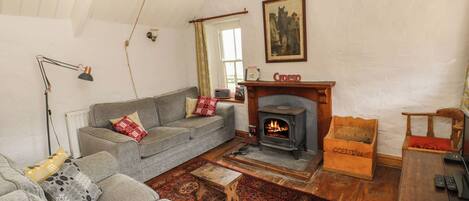 Un salon chaleureux avec une cheminée, un canapé, une chaise en bois et une petite table.