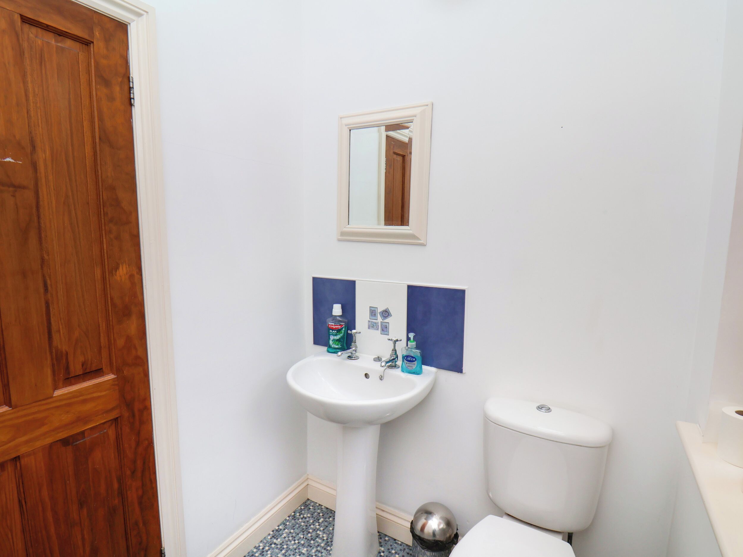 A bathroom with a white sink, a mirror above it, and a toilet.