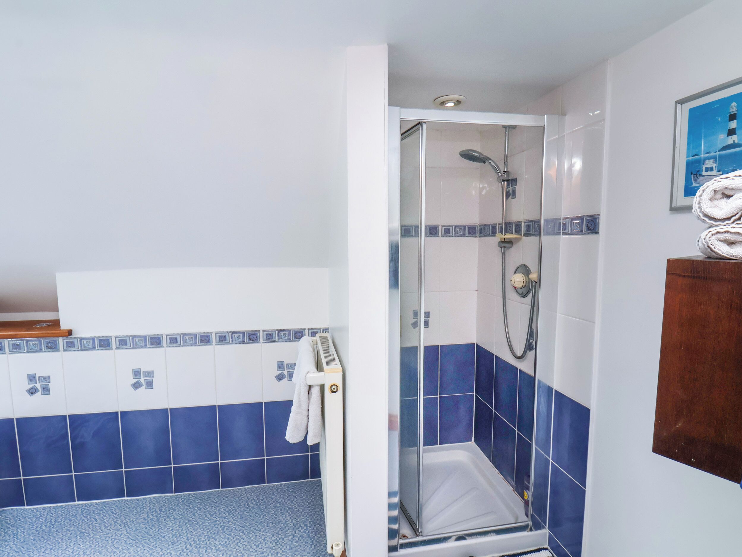Ein Badezimmer mit Dusche, gefliesten Wänden und einem Handtuchhalter.