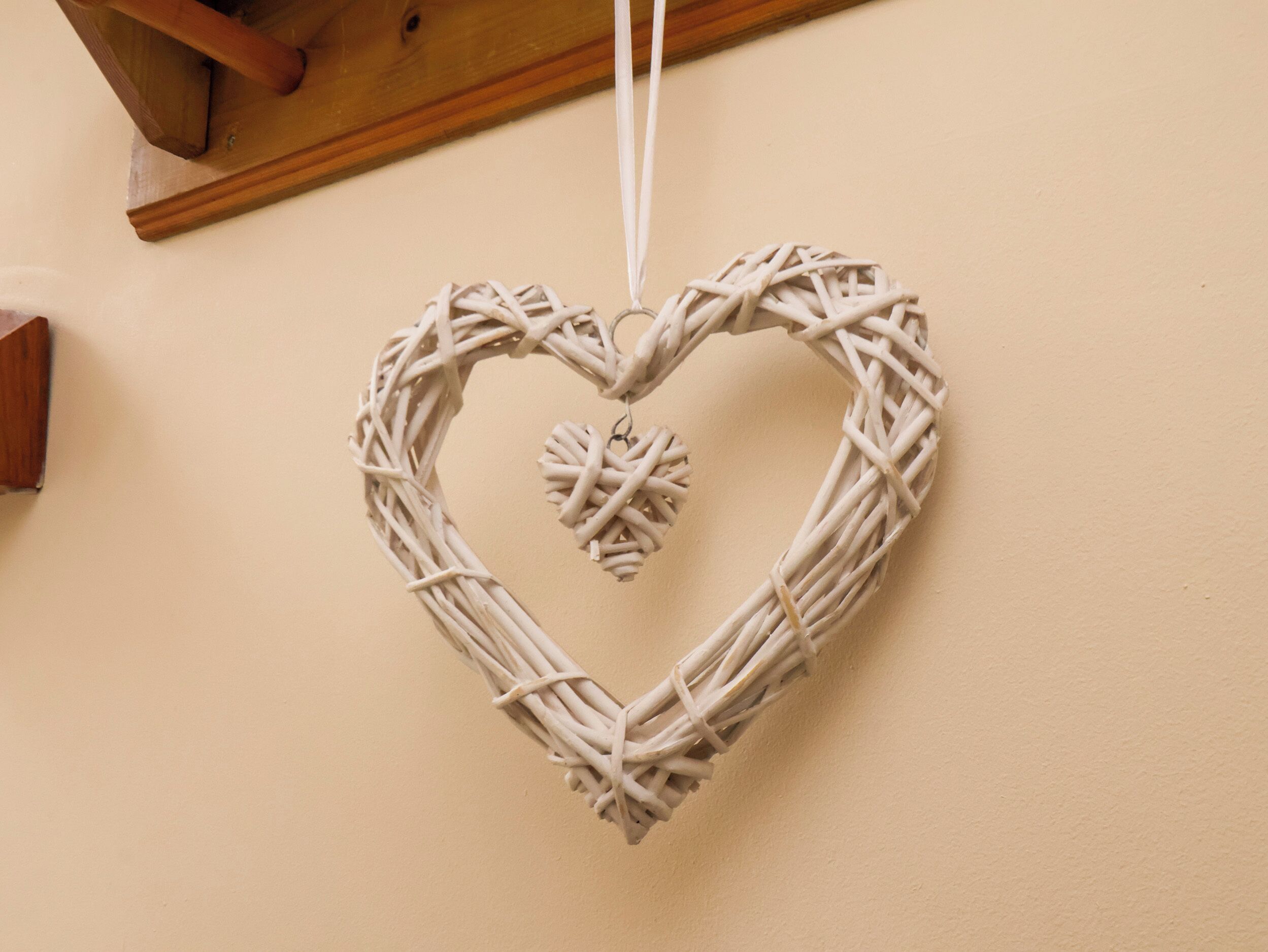 Decoración de mimbre con forma de corazón colgada en una pared.