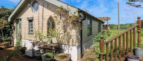 A quaint house with a wooden deck, potted plants, and a garden.