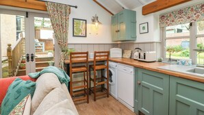 Cucina accogliente con mobili in legno, forno integrato e lavello. È presente una zona pranzo con tavolo e sedie, e una scala che conduce a un'area esterna.