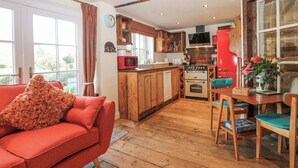 A cozy kitchen with wooden cabinets, a red refrigerator, and a dining area with a table and chairs. - The Bike Shed (Romsey)