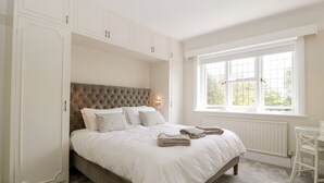 Ein Schlafzimmer mit einem großen Bett, eingebautem Kleiderschrank und einem Fenster mit Aussicht.
