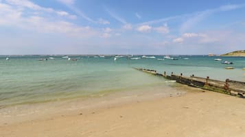 Ein Strand mit sandigem Ufer und einer Steinmole, die ins Wasser führt.