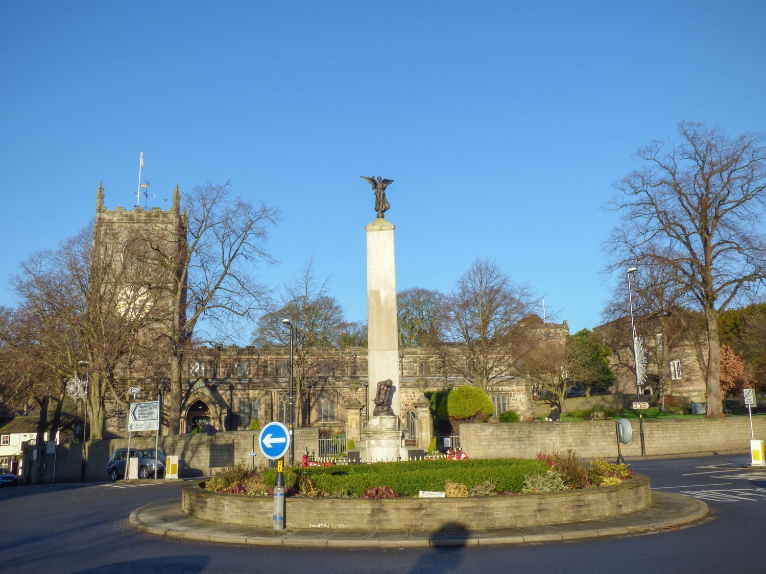 A roundabout with a central monument, a stone tower, and a clear blue sky.