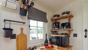 Eine Küche mit Holzausstattung, Spüle, Fenster und diversen Küchengeräten und Utensilien.