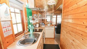 A compact kitchen with wooden walls, a sink, a stove, and a small refrigerator. - Touchwood Lodge (Narberth)