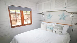 A bedroom with a bed, a window, and a headboard with decorative elements. - Touchwood Lodge (Narberth)