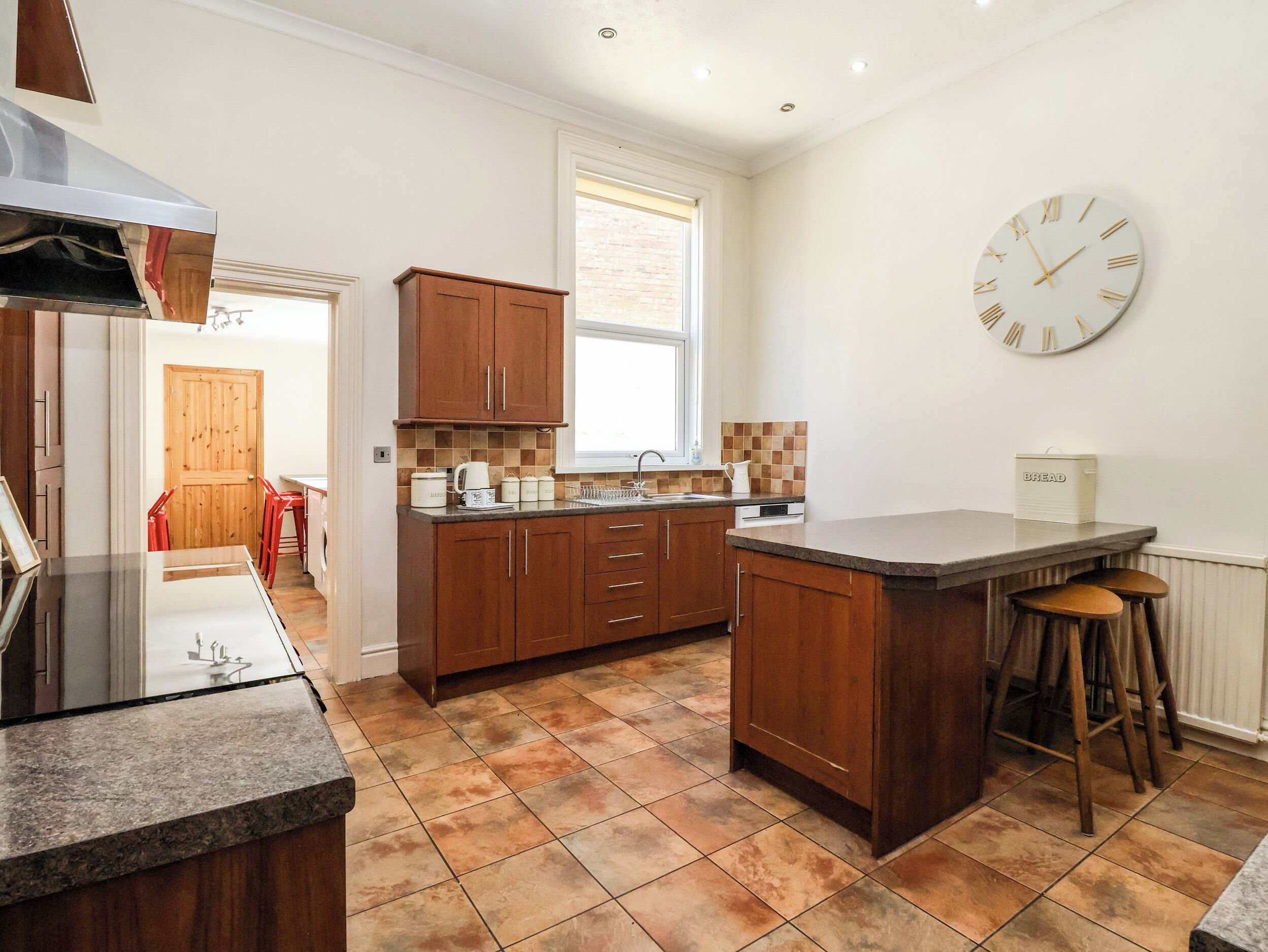 A modern kitchen with wooden cabinets, a granite countertop, and a large island with stools.