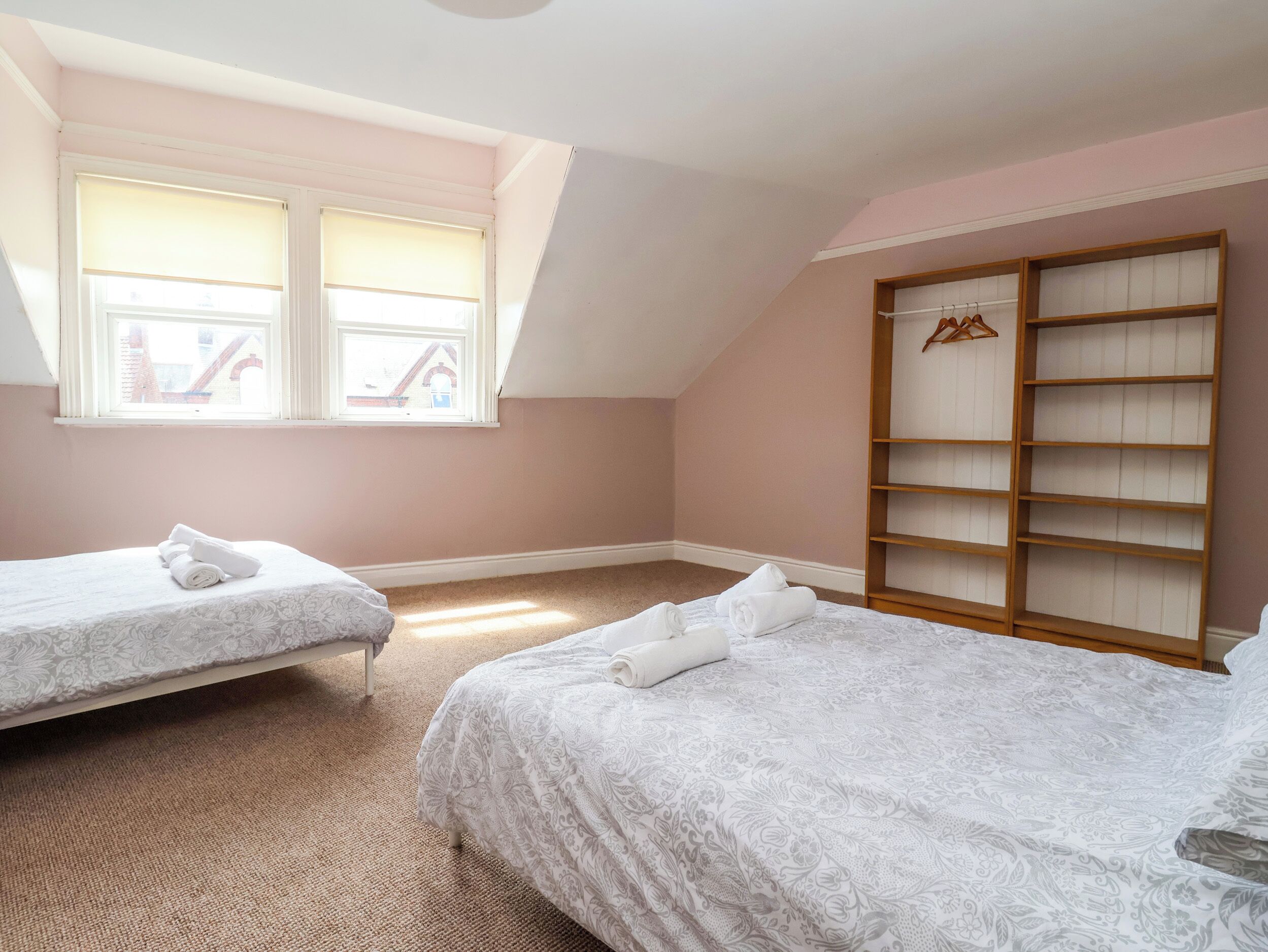 Ein Schlafzimmer mit zwei Betten, einem Fenster mit Jalousien, einem Holzschrank und Teppichboden.