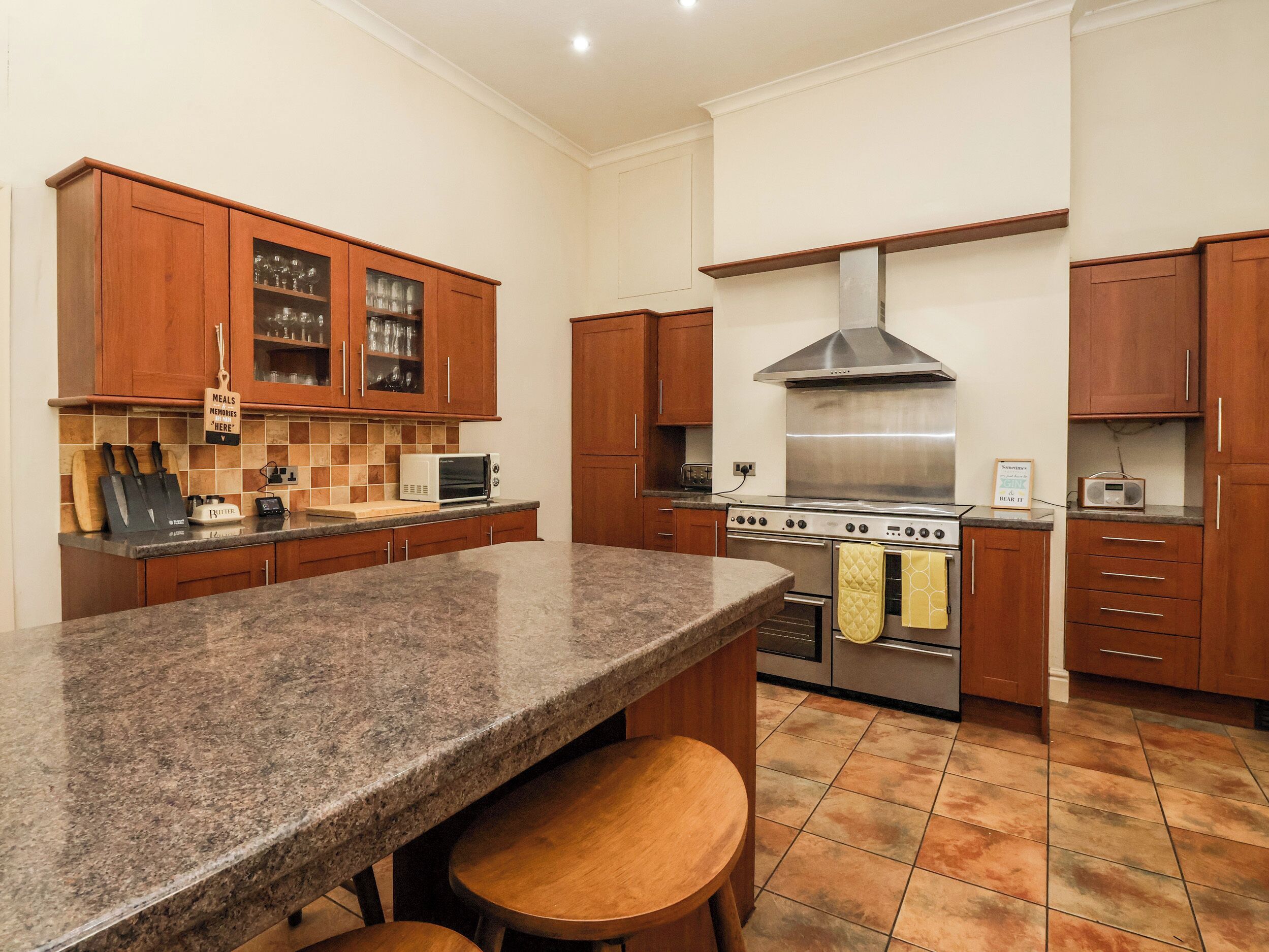 A kitchen with granite countertops, wooden cabinets, a stainless steel stove, and a microwave.