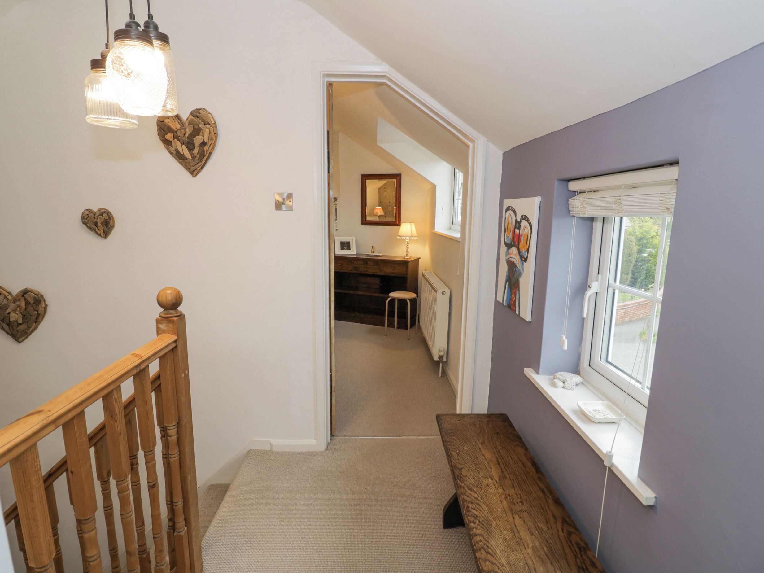 A staircase leading to a room with a wooden railing, a bench, and a window with a view.
