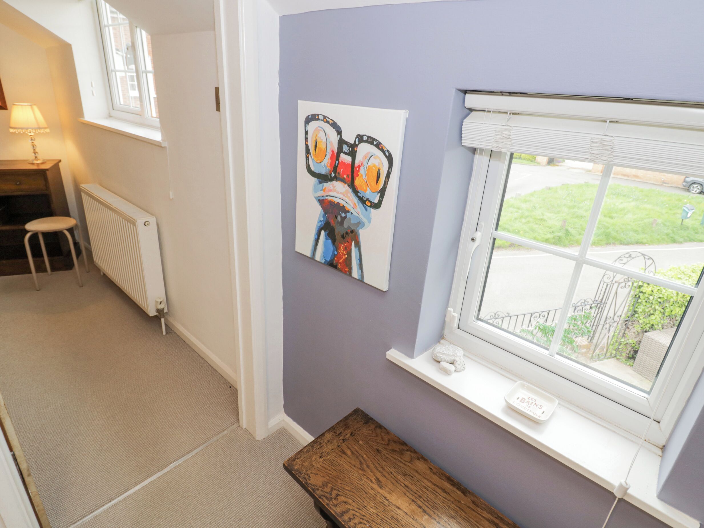 A room with a window, a radiator, a bench, and a chair.