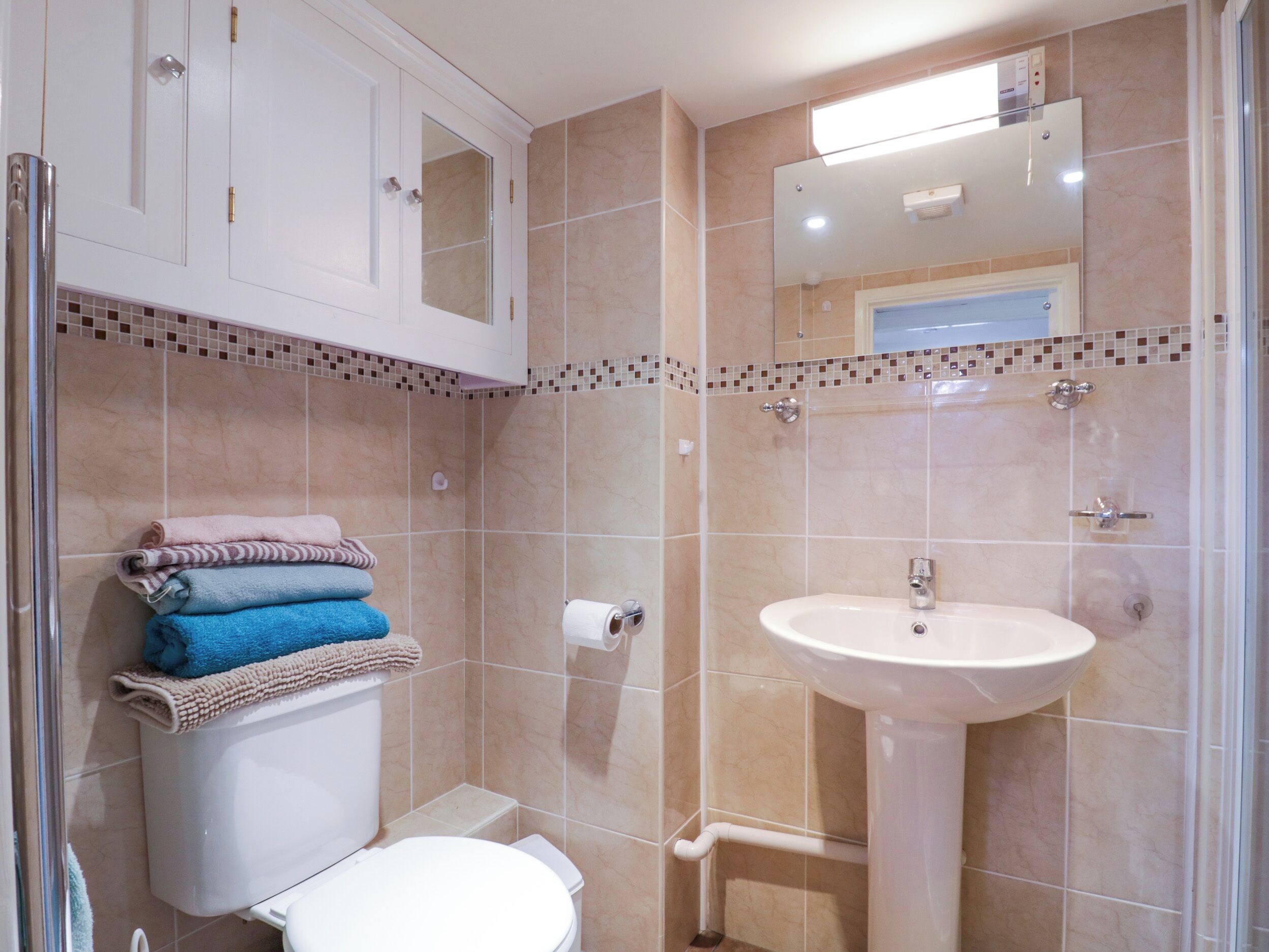 Un baño con inodoro, lavamanos y toallas apiladas.