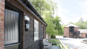 En tr æbygning med en mørk dør, et vindue og en bænk foran.