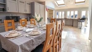 A dining area with a table set for four, wooden chairs, and a kitchen in the background. - Dolly's House (Middlewich)