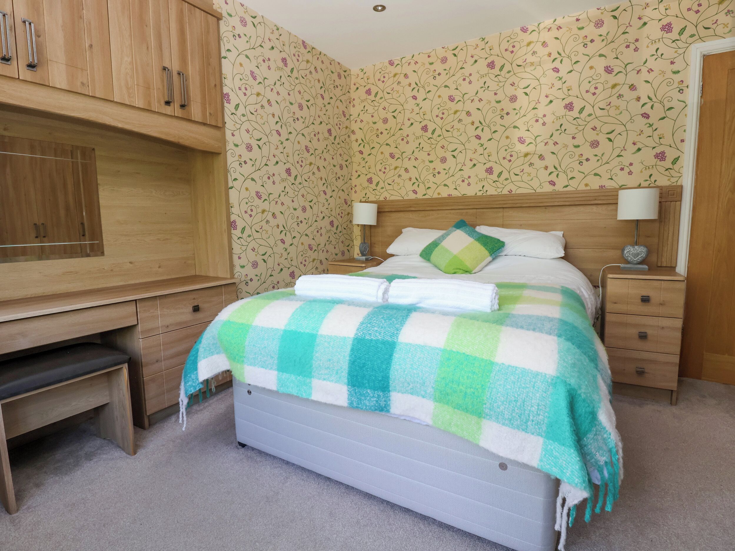 A bedroom with a bed, a desk, and a wardrobe.