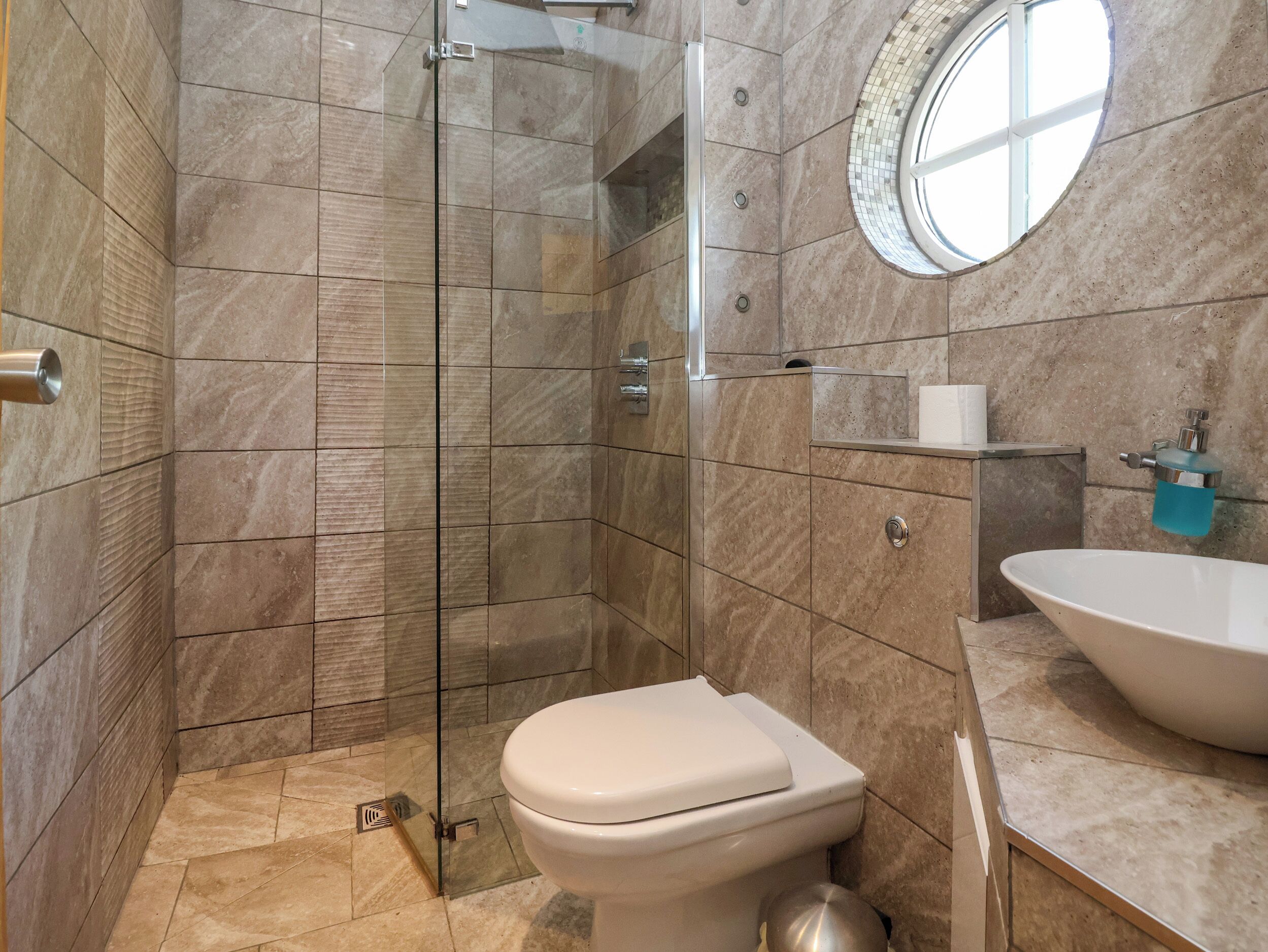Un bagno con doccia vetrata, un water e un lavandino con specchio sopra.