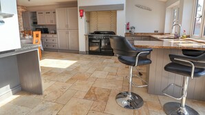 A modern kitchen with a gas stove, stainless steel appliances, and a bar area with stools. - Dolly's House (Middlewich)
