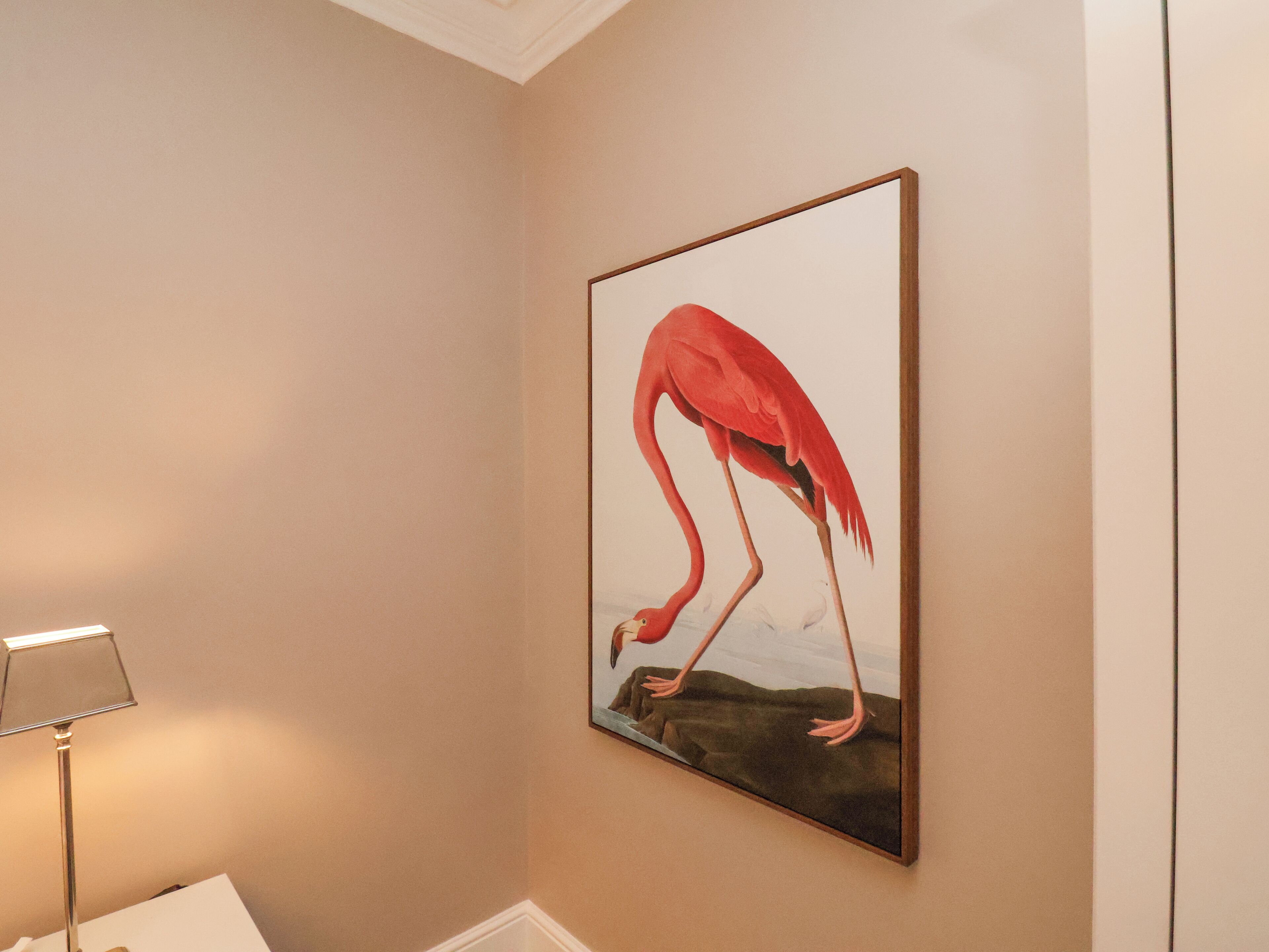 A framed painting of a flamingo on the wall.