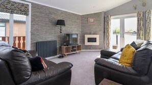 Una sala de estar moderna con chimenea, sofás de cuero, un televisor de pantalla plana y un ventanal con vistas al exterior.