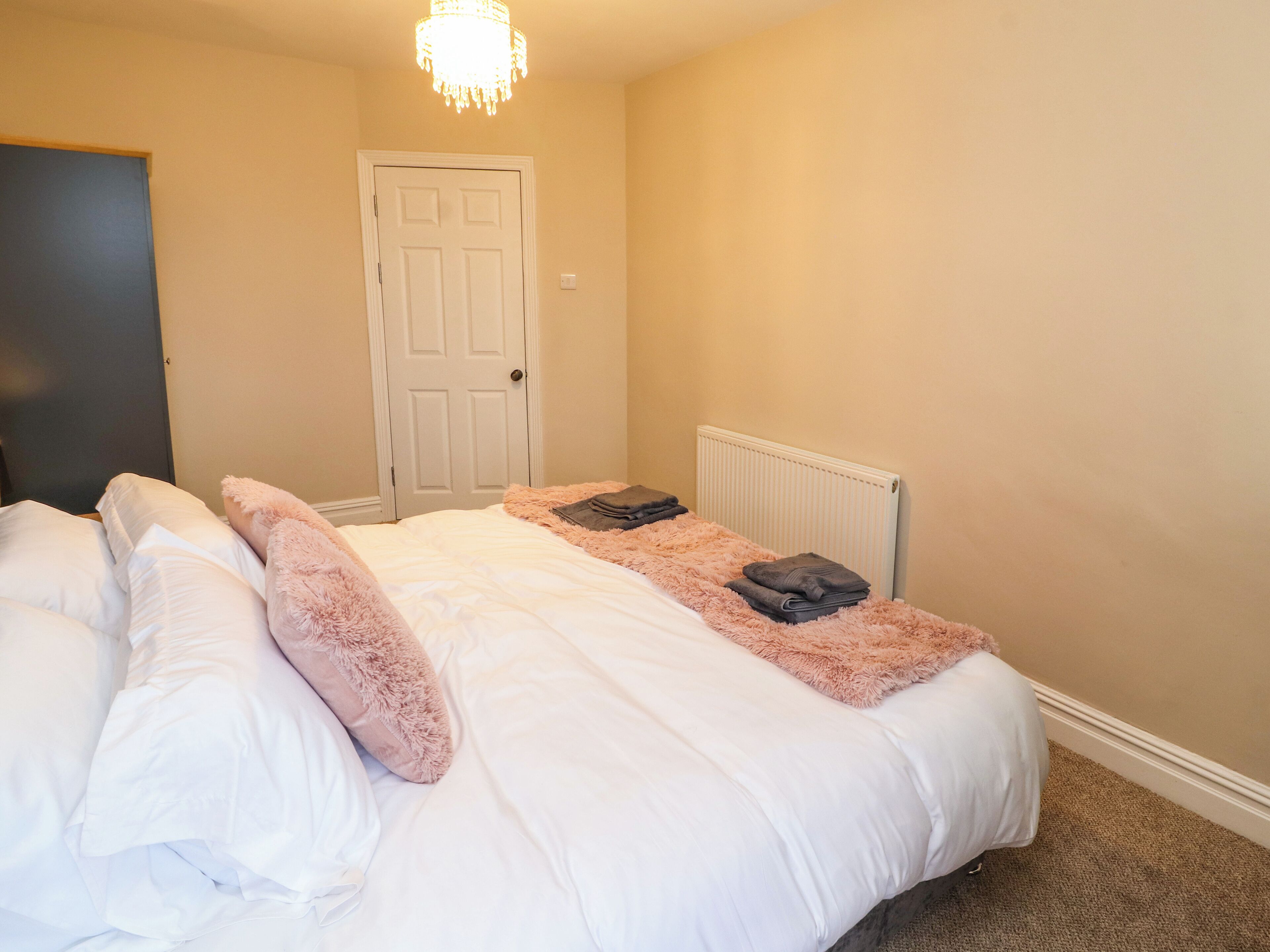 A bedroom with a large bed, a white door, and a radiator.