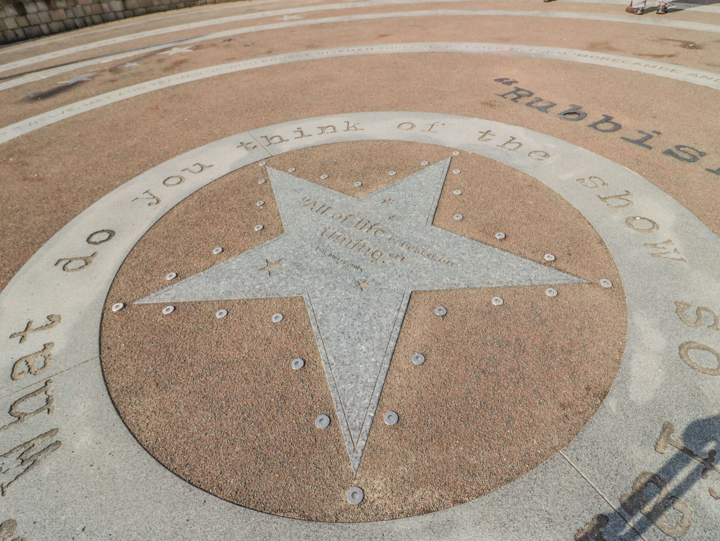 Pietra pavimentale a forma di stella con incisioni e chiodi metallici.