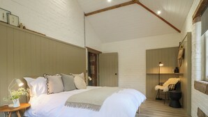 A bedroom with a large bed, bedside lamps, a small table with a vase, and a chair. - Beech Cottage - Fold Yards (Matlock)