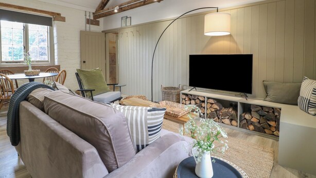 A cozy living room with a sofa, a TV, and a fireplace. - Beech Cottage - Fold Yards (Matlock)